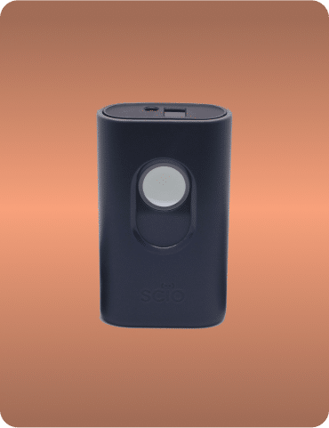 A small, rectangular black device with a button in the center on a gradient brown background. The word "SCiO" is printed near the bottom.