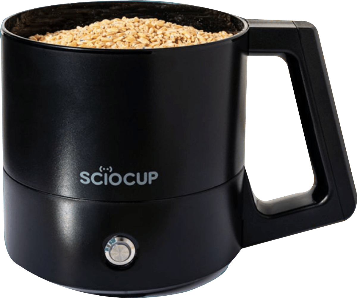 Black electric mug with logo "SCIOCUP," filled to the brim with small beige grains.