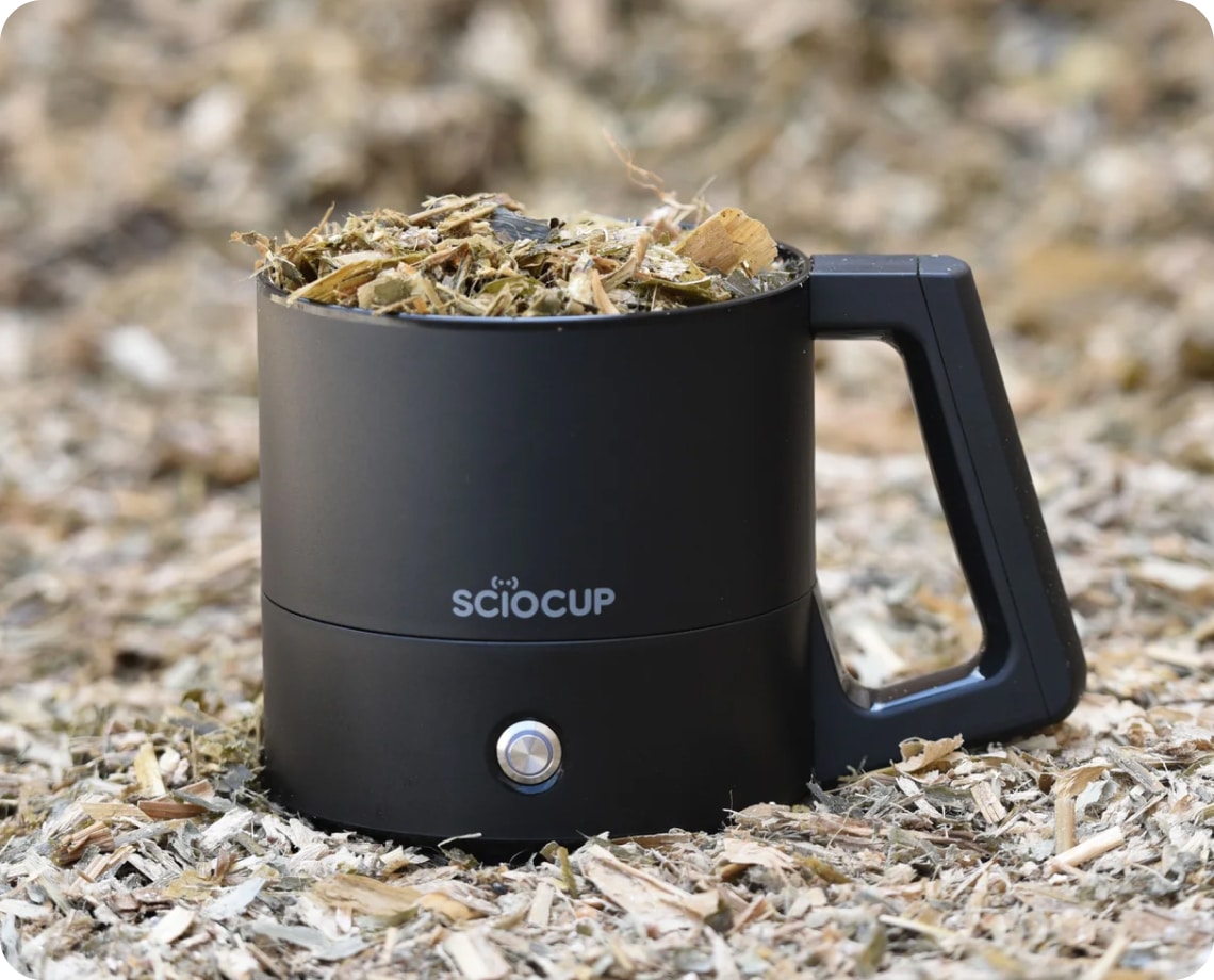 A black cup filled with wood chips sits on a pile of wood chips.
